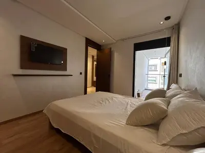 a bedroom with a bed with a television on the wall at Studio au Parc Mohammedia in Mohammedia