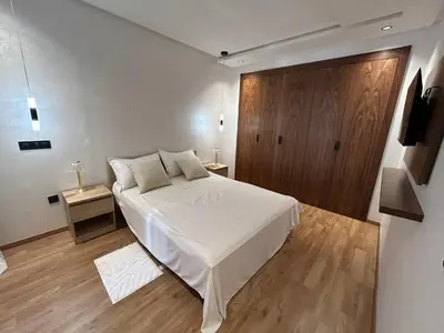 a bedroom with a white bed and a wooden door at Studio au Parc Mohammedia in Mohammedia