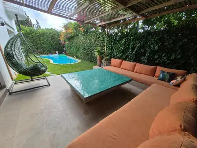 a patio with a couch and a swing and a pool at Beach Villa with Private Pool, Ideal for Families in Casablanca