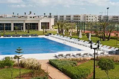 a swimming pool with lounge chairs and a building at Ola Blanca in Dar Hamida