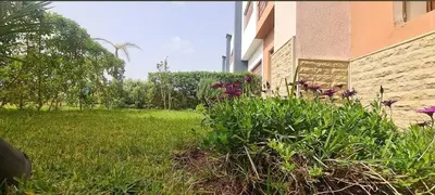 a building with purple flowers in the grass next to a building at Villa pied dans l'eau in Sidi Rahal