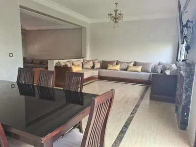 a living room with a table and chairs and a couch at Villa pied dans l'eau in Sidi Rahal
