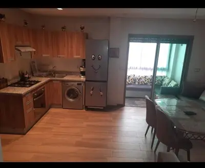 a kitchen with a stainless steel refrigerator and a table at Blue Beach sidi rahal in Sidi Rahal