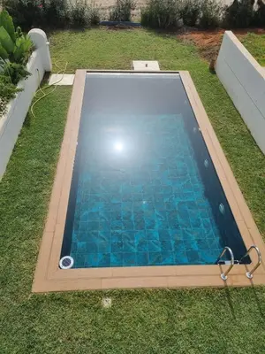 a swimming pool in a yard with blue water at Private villa with pool in Bouznika