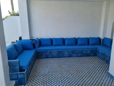 a blue couch sitting in the corner of a room at Private villa with pool in Bouznika