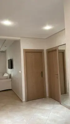 a room with two wooden doors and a couch at Appartement à Ritaj Beach in Casablanca