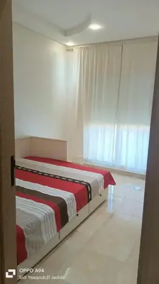 a bedroom with a bed with a red and white blanket at Appartement à Ritaj Beach in Casablanca