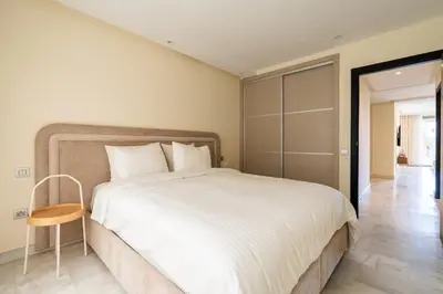 a bedroom with a large white bed and a chair at Le yacht apartment II Oceanfront residence 2 BR 2 BA in Casablanca