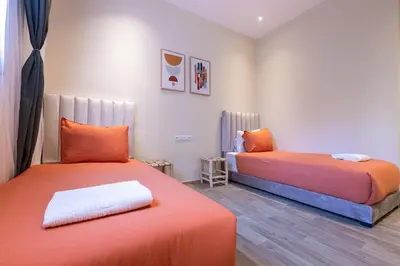 two beds in a room with orange sheets at 2BR Apartment in Prestigious Mahaj Riad by MERAT HOME in Rabat