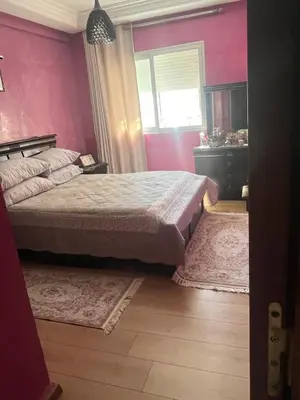 a bedroom with a bed with pink walls and a window at Rayan beach Residence avec picine a tamaris in Tamaris