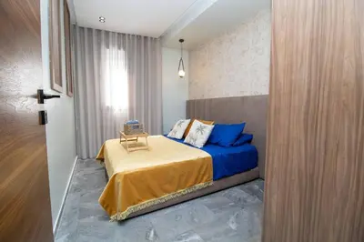 a bedroom with a bed with blue sheets and a window at Private terrasse and spa Studio Sahara in Casablanca in Casablanca