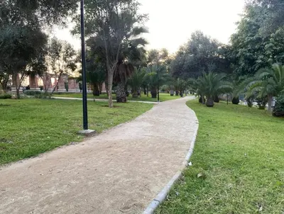 a walking path in a park with palm trees at cozy living, Chic 3BR appartement with parking! in Casablanca
