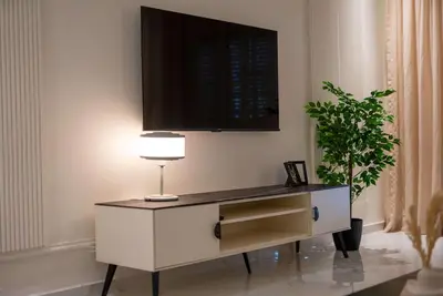 a desk with a lamp and a tv on a wall at Modern & Central 2BR Stay in Rabat in Rabat
