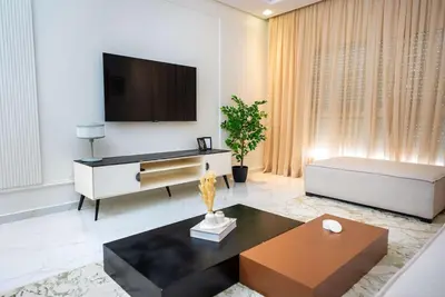 a living room with a couch and a tv on a wall at Modern & Central 2BR Stay in Rabat in Rabat