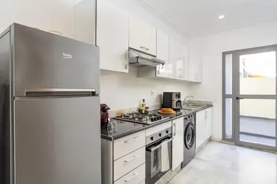 a kitchen with white cabinets and a stainless steel refrigerator at The Loft Residence by GoodMove - Maarif Casablanca in Casablanca