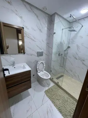 a bathroom with a shower and a toilet and a sink at Appartement Luxe Vue Piscine Résidence Les Perles de Bentriaa, El Mansouria in Mohammedia