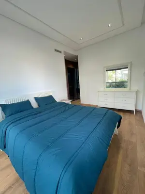 a large blue bed in a white room with a window at Appartement Luxe Vue Piscine Résidence Les Perles de Bentriaa, El Mansouria in Mohammedia