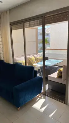 a living room with a blue couch and a balcony at Puerto banus appartement in Mohammedia