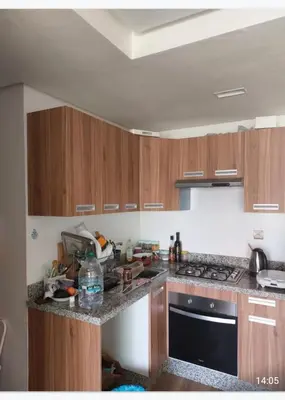 a kitchen with wooden cabinets and a stove top oven at Blue beach in Sidi Rahal