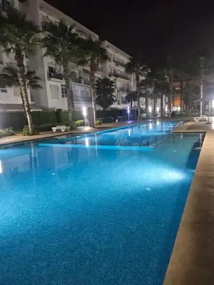 a large swimming pool at night with palm trees at Buznika marocco in Bouznika