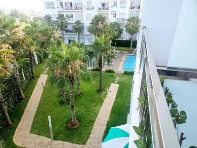 an apartment balcony with palm trees and a swimming pool at Buznika marocco in Bouznika