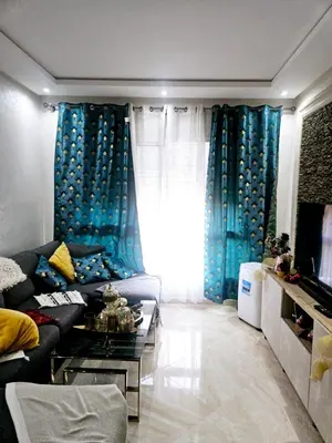 a living room with blue curtains and a couch at Buznika marocco in Bouznika