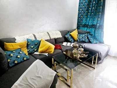 a living room with a couch with yellow and blue pillows at Buznika marocco in Bouznika