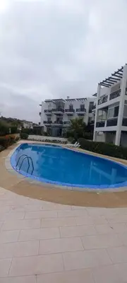 a large blue swimming pool in front of a building at Vue Mer & Sérénité, Appartement Chic avec Piscine à Dar Bouazza in Tamaris