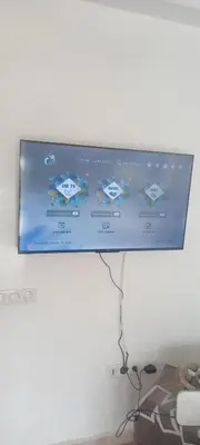 a flat screen tv hanging on a white wall at Vue Mer & Sérénité, Appartement Chic avec Piscine à Dar Bouazza in Tamaris