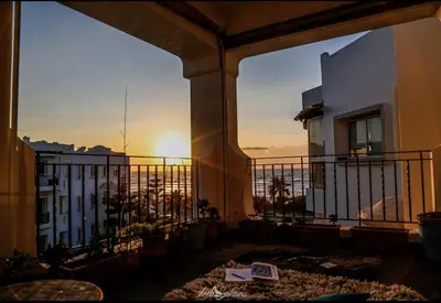 a balcony of a building with the sunset in the background at DarBouazza SurfHouse Sea View in Tamaris
