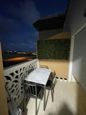 a table and chairs on a balcony at night at ossama in Mansouria