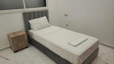 a small bed in a room with a night stand at Appartement familial vue piscine in Temara