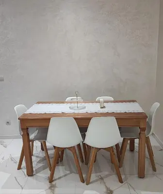 a wooden table with four white chairs around it at Appartement familial vue piscine in Temara