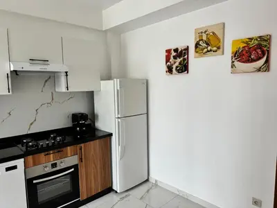 a kitchen with a white refrigerator and a stove at Appartement familial vue piscine in Temara