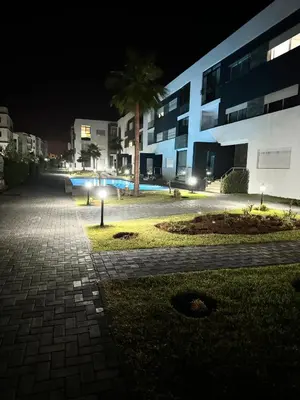 a night view of a building with a palm tree at Appartement familial vue piscine in Temara