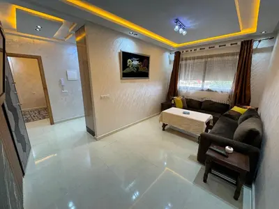 a living room with a couch and a table at Cozy modern apartment 3 min drive beach access in Sidi Rahal