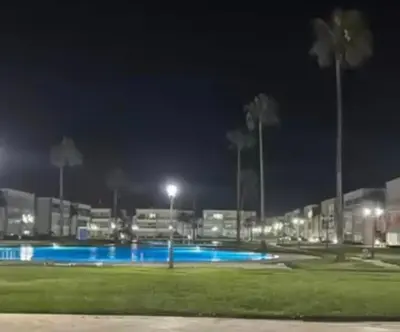 a night view of a parking lot with a pool at Résidence balnéaire casablanca in Dar el Maïzi