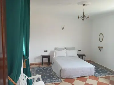 a bedroom with a white bed and a chandelier at Riad JOUHARA in Skhirat
