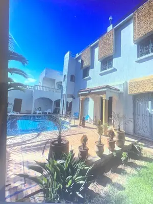 a large white building with potted plants in a yard at Riad JOUHARA in Skhirat