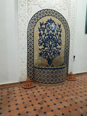 a fireplace in a room with a tile floor at Riad JOUHARA in Skhirat