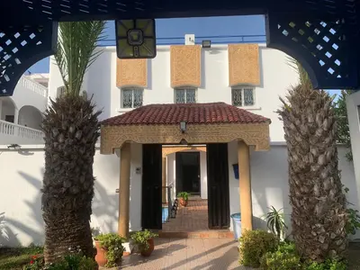 a white house with palm trees in front of it at Riad JOUHARA in Skhirat