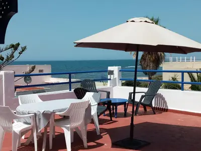 a table and chairs with an umbrella and the ocean at Riad JOUHARA in Skhirat
