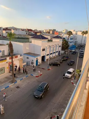 a city with cars parked on a street with buildings at Martil in Anfa-Supérieur
