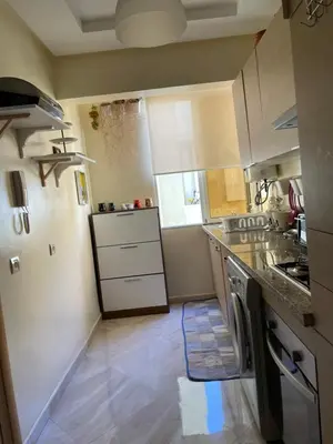 a kitchen with white cabinets and a counter top at lumineux appartement in Bouznika