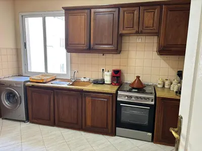 a kitchen with wooden cabinets and a stove and a dishwasher at Havre de paix au centre de Casablanca in Casablanca