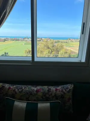 a window with a couch looking out at a field at Détente et confort en face de mer in Casablanca