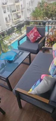 a balcony with two chairs and a table and a pool at Appartement vue sur piscine kettani in Bouznika