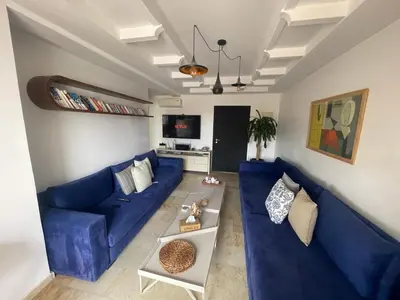 a living room with a blue couch and a table at Sun Darb in Dar Bouazza