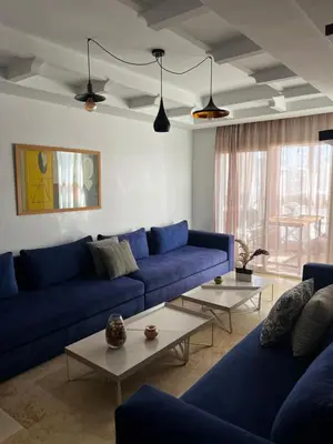 a living room with blue couches and tables at Sun Darb in Dar Bouazza