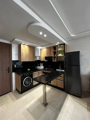a kitchen with a black refrigerator and wooden cabinets at Nouvel Appartement Parc Mohammedia in Mohammedia